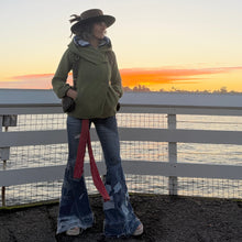 Load image into Gallery viewer, Person standing by a fence with a sunset over water in the background