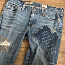 Load image into Gallery viewer, Upcycled from a collection of salvaged denim threads. Base jeans are from Adriano Goldshmied "The Stilt" womens size 28, and in excellent condition! Some give/stretch denim with intentional distress, and embroidered stitching over distressed areas. Added denim bits and pieces to create wide-flared bottoms.
Handcrafted with love and intention.
One-of-a-kind
Funky vibes
Size 28
Cold wash, like you would any pair of jeans, for longevity
Handmade in Santa Cruz, CA