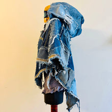 Load image into Gallery viewer, Upcycled from a collection of salvaged denim pants. Oversized hoodie, sprinkles of sashiko stitching, random pockets, a lots of intentional distress. Lightweight, with more denim for ties on the sides to keep a little fitted to your body. A perfect layer of warm and fresh. 
Handcrafted with love and intention.
Upcycled Capelet Jacket
Urban vibes
One-of-a-kind
All size
Handmade in Santa Cruz, CA
