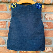 Load image into Gallery viewer, Upcycled from selvedge jean scrap and African remnant fabric. Lined for warmth and durability, with two pockets for all those found magical treasures. This spirit vest is lightweight yet made for play and fun flare. A perfect colorful and eclectic layer of love!   Handcrafted with love and intention.   Upcycled and one-of-a-kind Button and cord clasp Lined and with two front pockets  Lightweight Handmade in Santa Cruz, CA Cold wash, hang dry