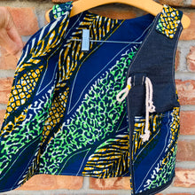 Load image into Gallery viewer, Upcycled from selvedge jean scrap and African remnant fabric. Lined for warmth and durability, with two pockets for all those found magical treasures. This spirit vest is lightweight yet made for play and fun flare. A perfect colorful and eclectic layer of love!   Handcrafted with love and intention.   Upcycled and one-of-a-kind Button and cord clasp Lined and with two front pockets  Lightweight Handmade in Santa Cruz, CA Cold wash, hang dry