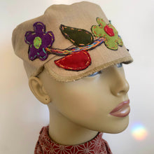 Load image into Gallery viewer, One of a kind design elements and embellishments upcycled from salvaged remnant fabric scraps, and hand sewn in Santa Cruz, CA. 100% cotton cap, handmade in Bali.   Floral embroidered embellishments Tan colored cap Flower power vibes 100% cotton US size 7 1/4" *  Wash cold, hang dry *see size chart for detailed measurement