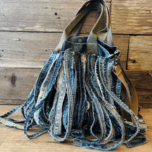 Load image into Gallery viewer, Upcycled from a whole lotta salvaged denim scraps, carefully sewn onto a salvaged denim bag with one interior pocket. This bag has both hand straps, as well as a shoulder strap for versatility! Not only are you choosing eco conscious with using textiles saved from the landfill, this bag is super unique and fly! DENIM DENIM DENIM!

Handcrafted with love and intention.

One-of-a-kind
Denim vibes

Handmade in Santa Cruz, CA
