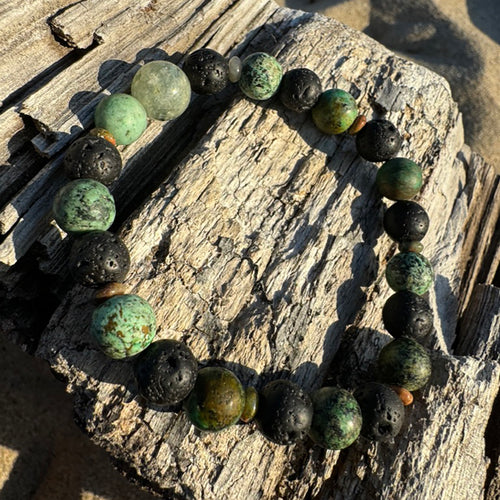Center stone: Prehnite Associated to the heart chakra, opening the heart to unconditional love, healing emotional wounds, and promoting self-love and forgiveness.  African Turquoise: Supports the immune system, relieving pain and discomfort, and promote overall well-being. Stone of creativity, abundance and self-expression.  Lava Stone: A grounding stone that strengthens one's connection to mama earth.  Unakite (spacers): Assists with emotional healing, forgiveness, letting go. 