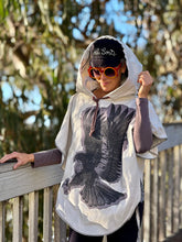 Load image into Gallery viewer, Upcycled from cotton lightweight canvas curtain and a salvaged Sure Design cotton t-shirt. Intentional revealed stitching, hand embroidered stitching for extra detail and whimsy, an oversized hood and side ties to give the option of more fitting or free flowing.

This poncho is lightweight, super cozy and total vibes for that walk along the beach, on your way to yoga class, or even out to dinner with your bestie! Easily rolls up so you can bring that extra layer of warm and fly with you anywhere!!!

Made of
