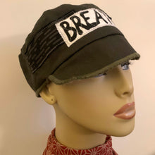 Load image into Gallery viewer, One of a kind design elements and embellishments upcycled from salvaged remnant fabric scraps, and hand sewn in Santa Cruz, CA. 100% cotton cap, handmade in Bali.   It&#39;s medicine: BREATHE  Army green colored cap High vibration  100% cotton US size 7 3/8&quot; *  Wash cold, hang dry *see size chart for detailed measurement
