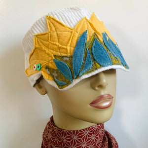 One of a kind design elements and embellishments upcycled from salvaged remnant fabric scraps, and hand sewn in Santa Cruz, CA. 100% cotton cap, handmade in Bali.   Yellow, blue and green elements  White ribbed cap One-of-a-kind Festive fire vibes Button and faux fur embellishments US size 7 5/8" *  Wash cold, hang dry *see size chart for detailed measurement