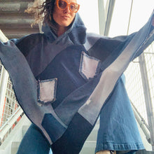 Load image into Gallery viewer, Upcycled from a collection of salvaged demin pants, a vintage denim curtain, and a denim jacket. Lightweight and flowy, with oversized hoody. A little combo between hippie and funky fly! Some denim pieces were already with intentional distress or otherwise well-loved and delicious. Two reversed pockets, raw side up with intention, perfect for sprinkles of little things. This piece is the perfect lightweight layer of warmth and FLY.   Handcrafted with love and intention.  Upcycled poncho Vintage jean vibes
